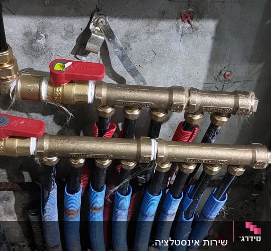 צינורות פלסטיק עם ברזי פליז אדומים בקיר
